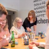 Participants working on their jewelry pieces while the instructor gives advice – creative team activity at Atelier Mein Meisterwerk in Basel.